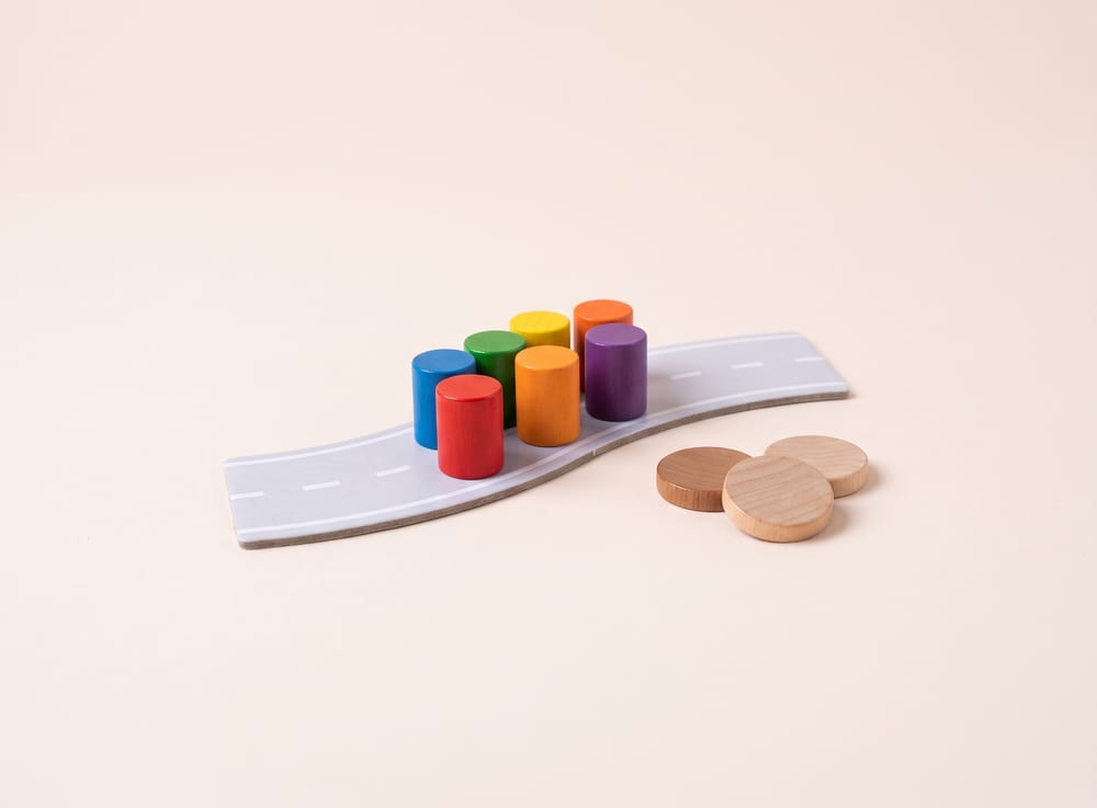 Six brightly painted wooden game markers packed together like a bunch of riders on a strip of road tile.