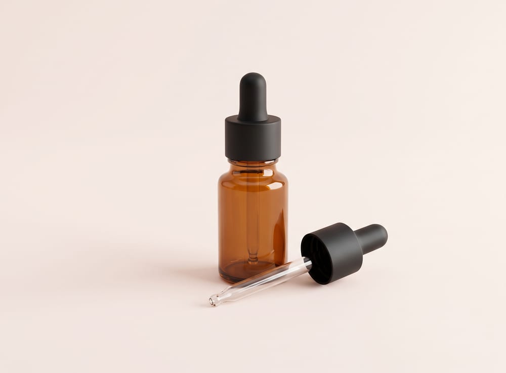 A small amber glass dropper bottle with its dropper resting beside it.